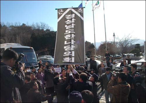 도의회 직원들이 시민단체가 갖고온 천으로 된 간판을 빼앗으려 하고 있다. 